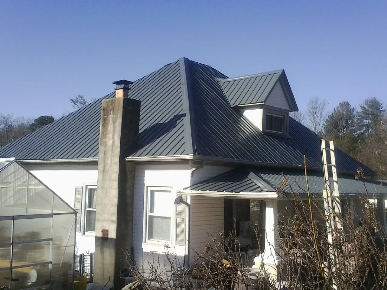 Dark blue standing seam metal roof on a white farmhouse with dormer — Slate & Tile Roof Repair by Roofing Brothers in Tecate