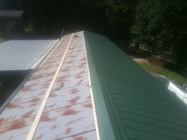 Old rusted panels beside newly installed green metal roofing — Wind Damage Roof Repair by Roofing Brothers in Tecate