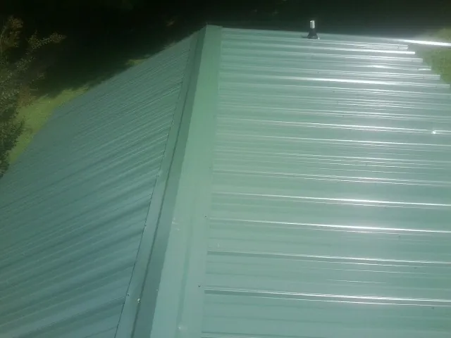 New green metal panels meeting at the ridge of a roof — Flat Roof Repair work by our crew in Tecate
