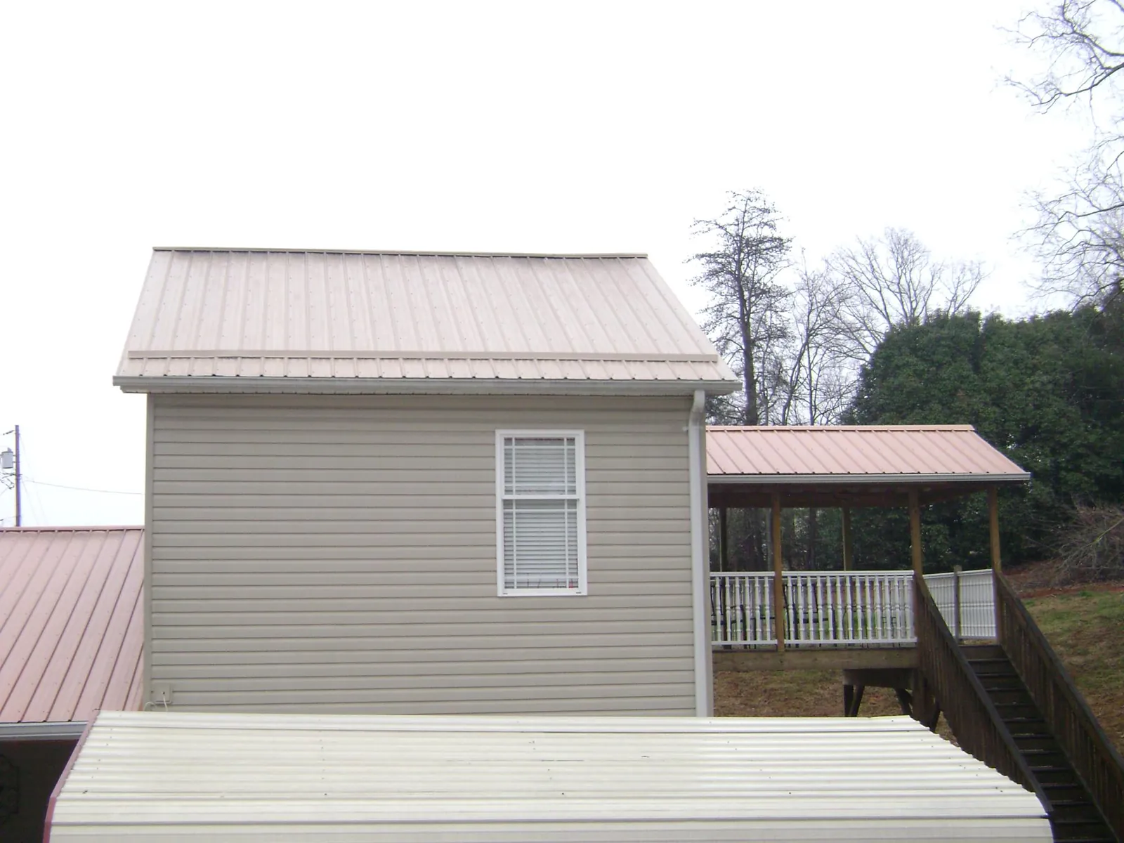 Tan metal roofs on a two story addition and attached porch, from a Roof Replacement job in Tecate
