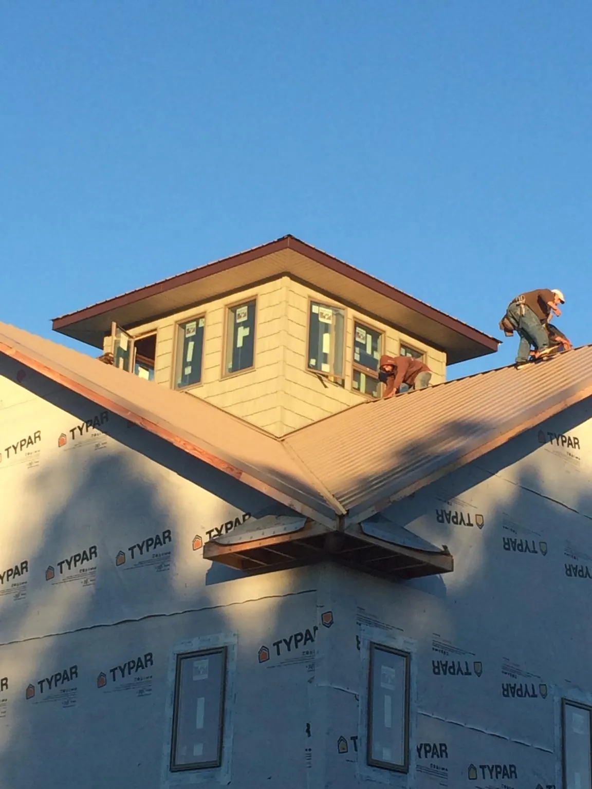 Roofers working around a rooftop cupola on a new metal roof at sunset — Roof Waterproofing in Tecate by Roofing Brothers